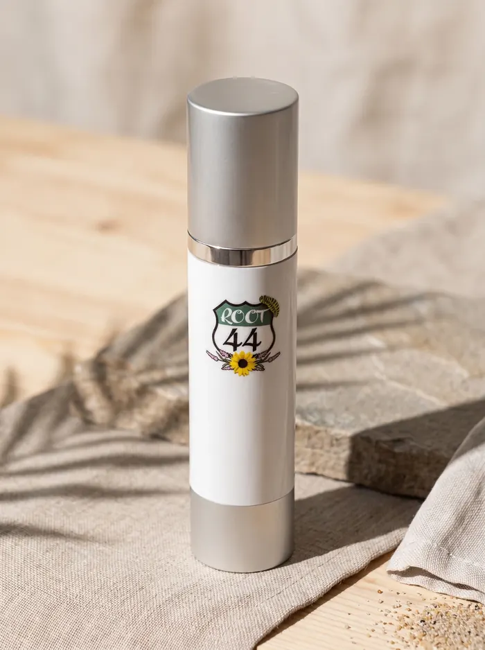 Root 44 Hyaluronic Serum standing on stone and linen in warm sunlight